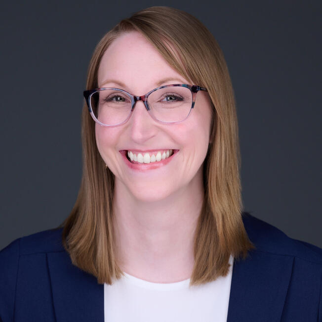 Woman with long blonde hair and hoop earrings smiling